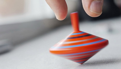 Hand playing with spinning top - knowing how to pivot in business is the key to a successful realignment